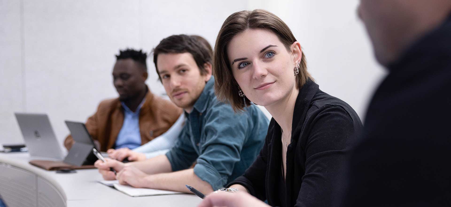 Two students in a classroom look at another student as they speak