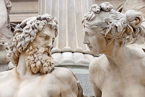 A marble statue of a man and a woman looking at one another.