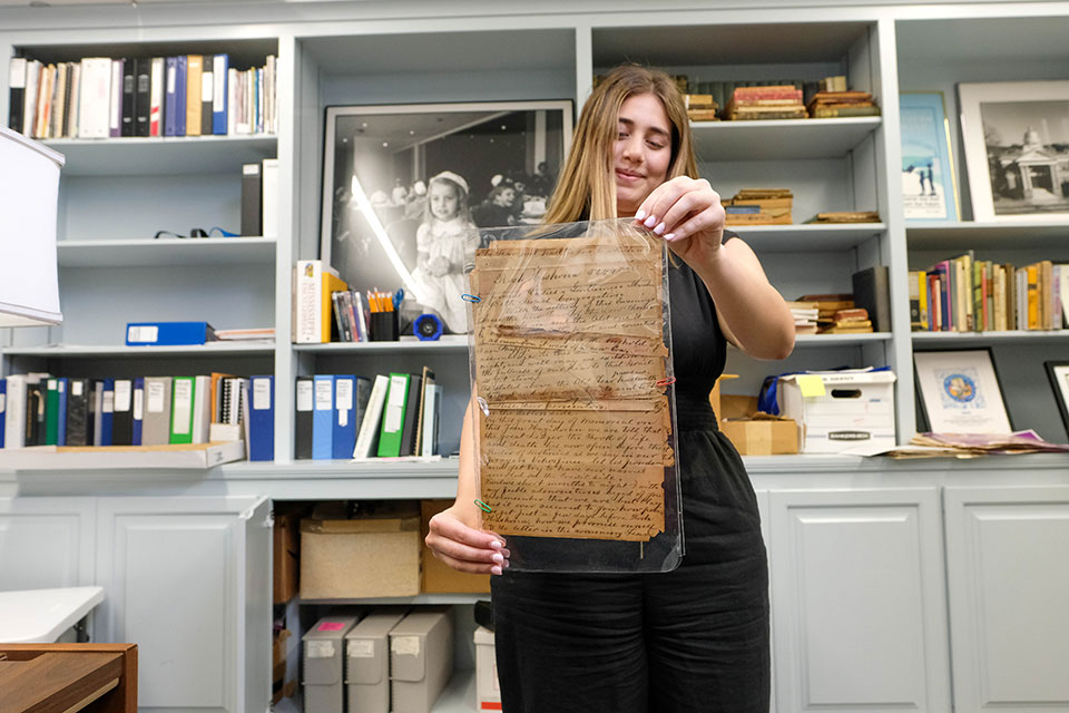 Lauren Balfour holds up an antique document.