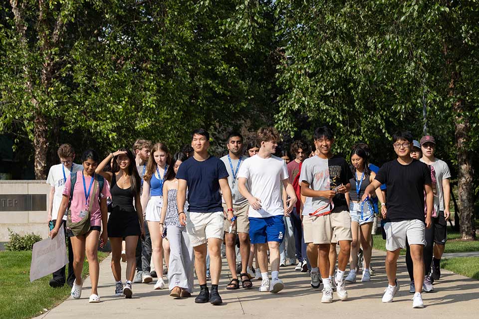 A group of new students walking on campus with their Orientation Leader.