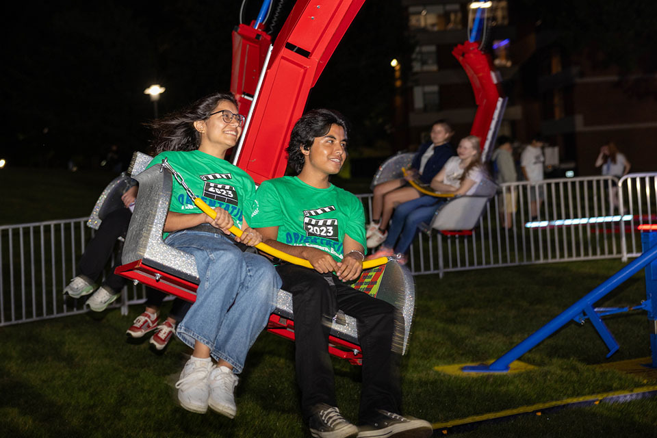 Two Orientation Leaders on a carnival ride at an Orientation evening event.