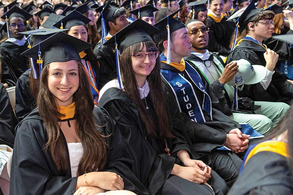 Students smiling at Commencement inside Gosman