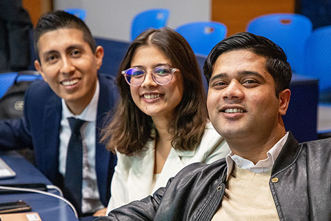 Three students smile in a classroom