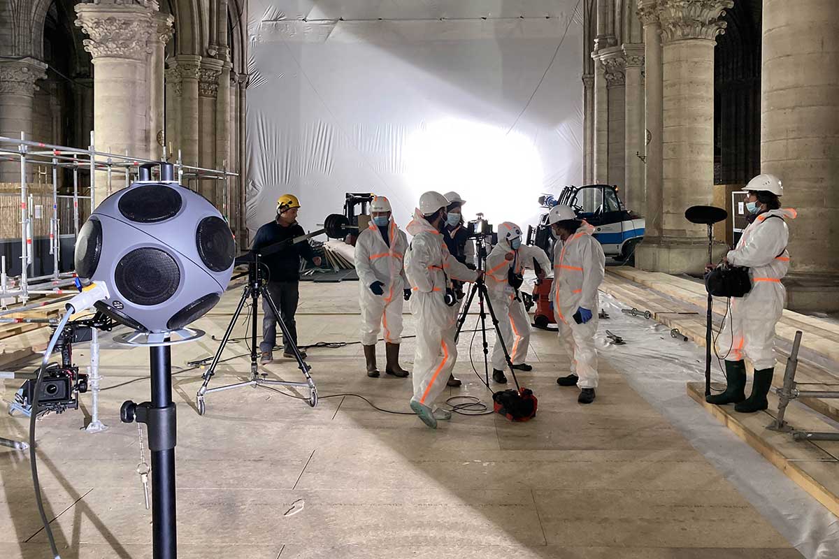 A group of people wearing protective clothing work inside of the Notre-Dame Cathedral.