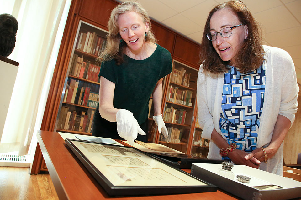Two Brandeis staff members review a historical document.