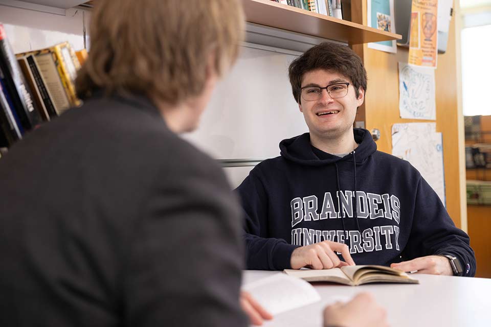 A student wearing a Brandeis sweatshirt smiling