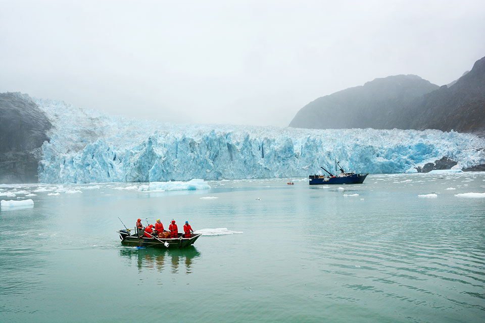 Two boats in front of a large glacier.