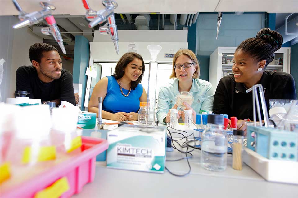 Students and an instructor gathered around a lab table
