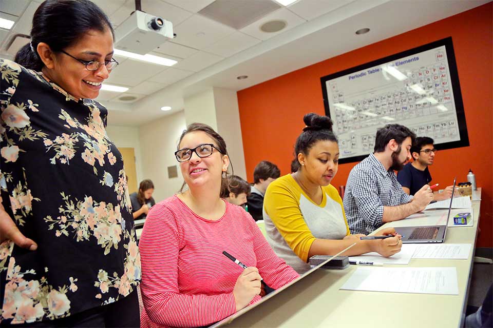 A professor checks in on a student at her desk