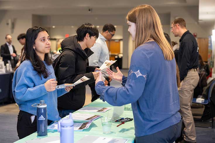 An employer speaks to a Brandeis student during a career fair.