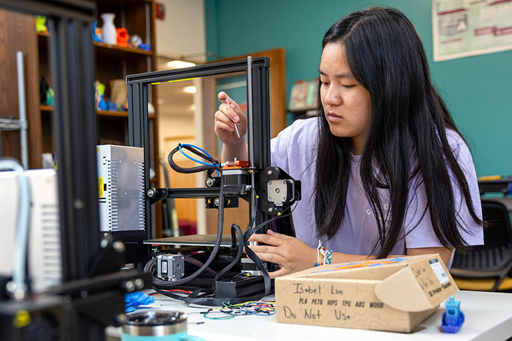 A student using a machine in the MakerLab