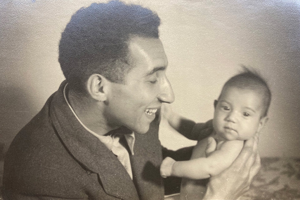 A man smiling while holding a baby.