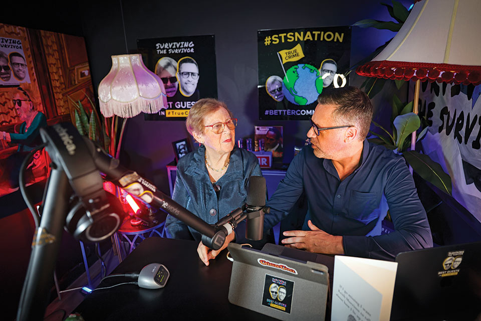 Two people, Joel and Karm Waldman, with podcast equipment