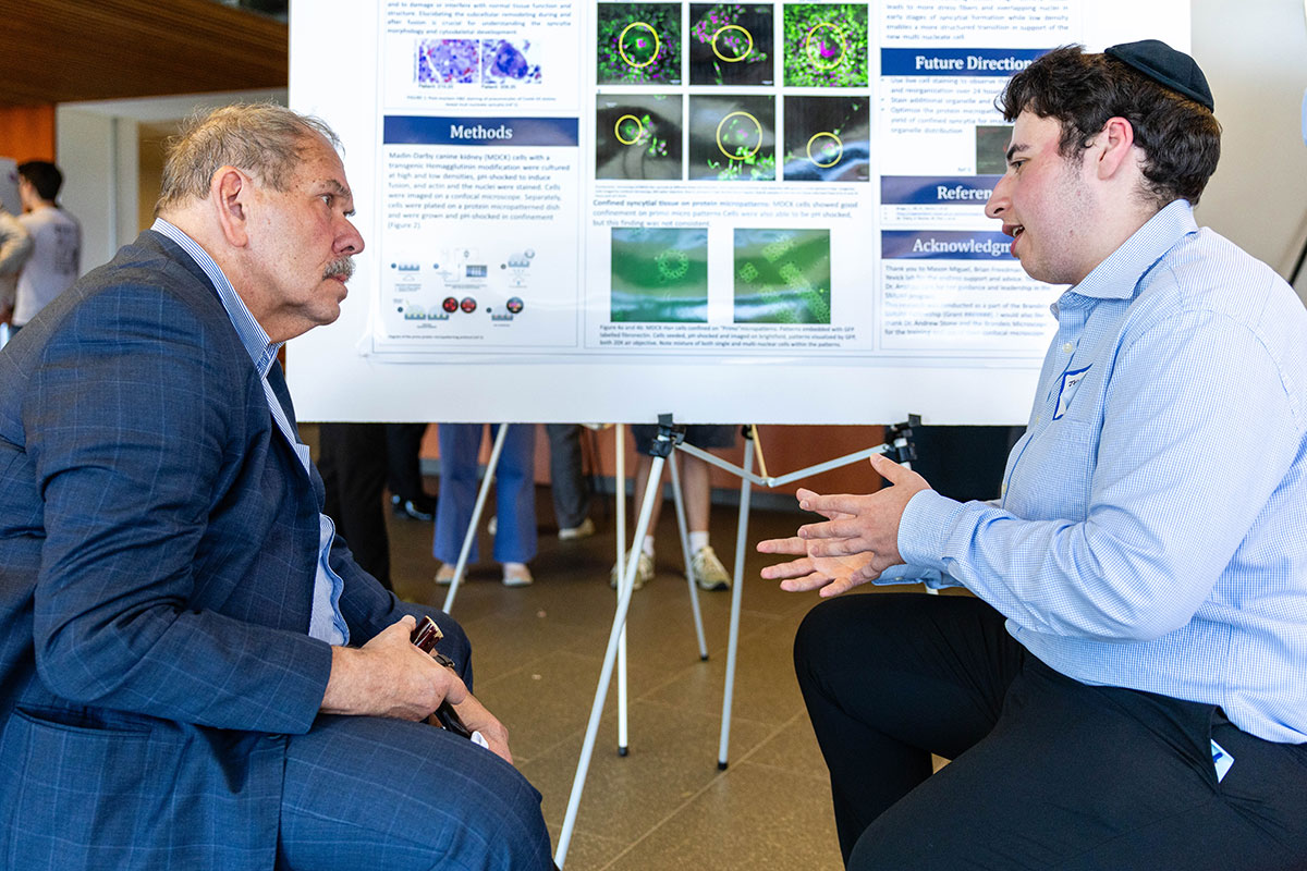 Vorchheimer discusses his research poster with Brandeis President Arthur Levine 