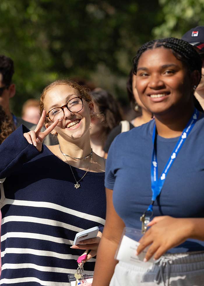 Two students smile and one holds up a peace sign.